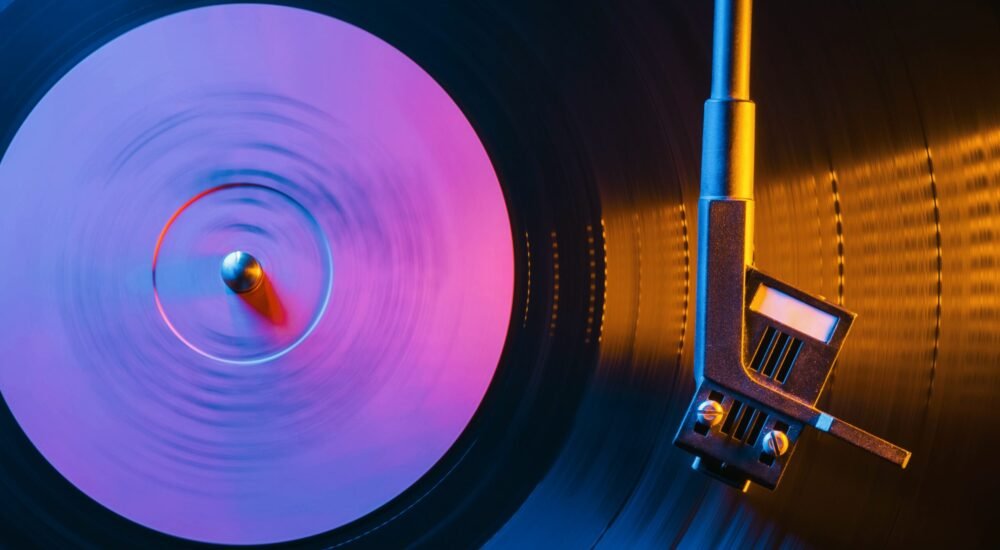 Movie of retro-styled record player spinning vinyl black record. Cinemagraph. Side view. Beautiful neon night colors.