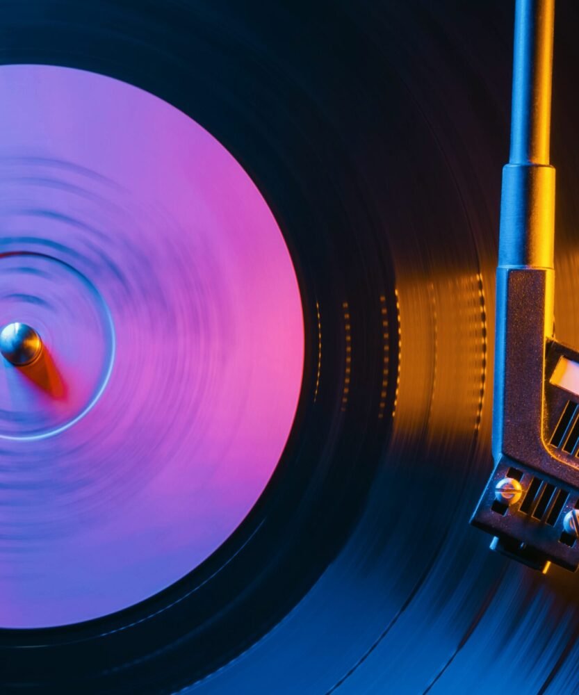 Movie of retro-styled record player spinning vinyl black record. Cinemagraph. Side view. Beautiful neon night colors.